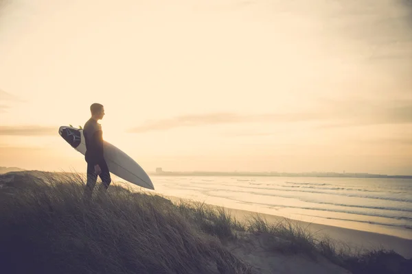 Surfista nas dunas olhando para as ondas — Fotografia de Stock