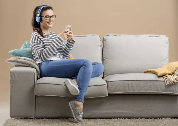 Mujer sentada en un sofá y escuchando música — Foto de Stock