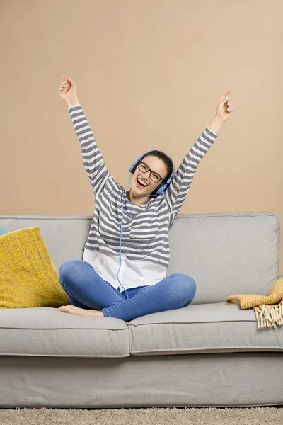 Kvinna sitter på soffan och lyssna på musik — Stockfoto