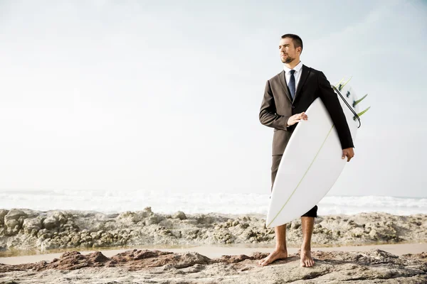 Geschäftsmann hält sein Surfbrett am Sandstrand — Stockfoto