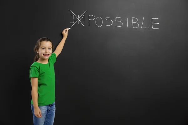 Girl writing in a blackboard — Stock Photo, Image