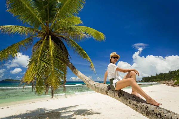 Vrouw zitten op een palmboom — Stockfoto