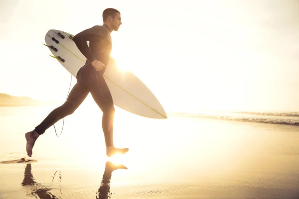 Surfer läuft mit Surfbrett auf Wellen zu — Stockfoto