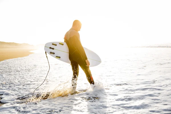 Surfer läuft mit Surfbrett auf Wellen zu — Stockfoto