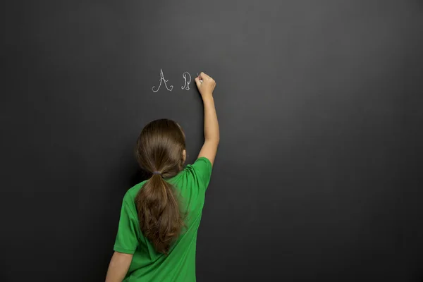 Girl writing in a blackboard — Stock Photo, Image