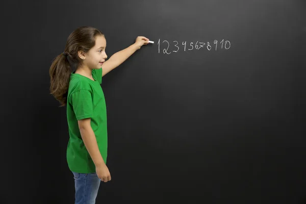 Girl writing in a blackboard — Stock Photo, Image