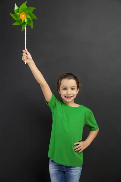 Chica oliendo y sosteniendo un molino de viento — Foto de Stock