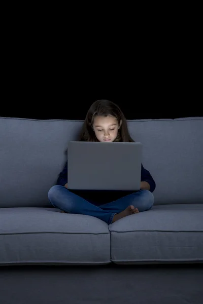 Маленькая девочка на диване работает на ноутбуке — стоковое фото