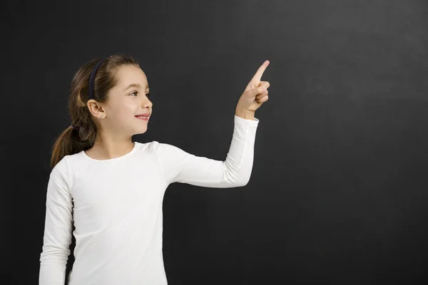 Little girl pointing to a blackboard — Stock Photo, Image