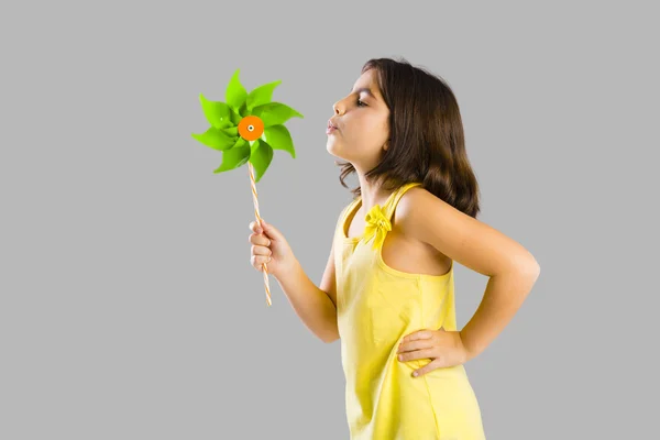 Menina soprando um moinho de vento de plástico — Fotografia de Stock