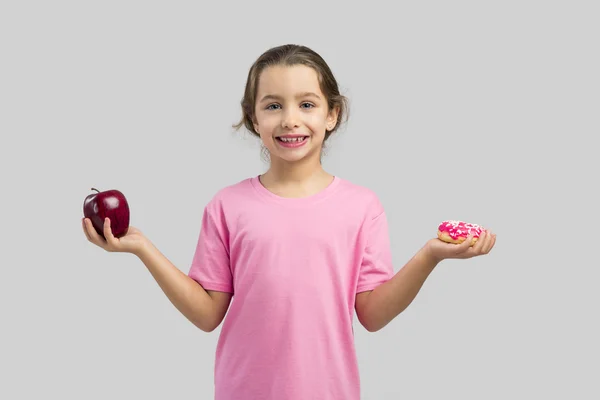 Chica eligiendo entre una manzana y un donut — Foto de Stock