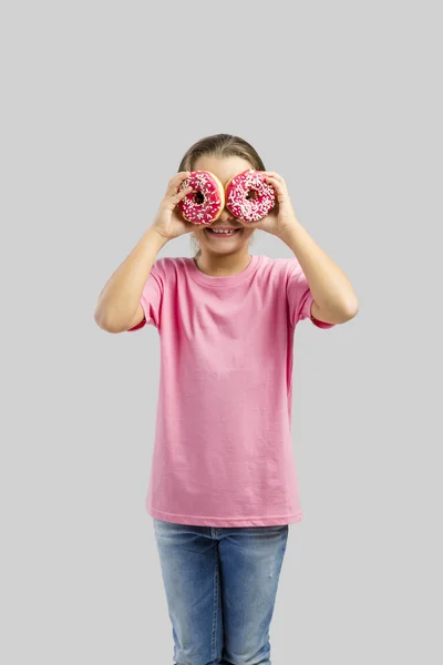 Meisje kijkend door donuts — Stockfoto