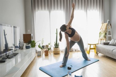 Hamile kadın evde egzersiz yapıyor.