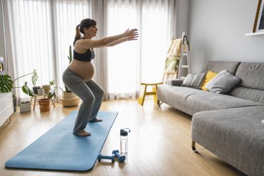 Hamile kadın evde egzersiz yapıyor.