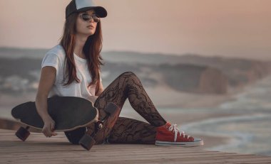 Güzel ve moda genç bayan kaykayla poz veriyor.