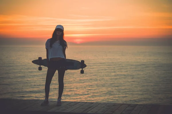 美丽而时尚的年轻女子 带着滑板 在夕阳西下的时候摆出一副姿势 有点吵闹 — 图库照片