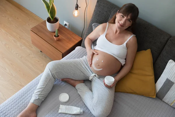 Gravid Kvinna Applicera Bristning Grädde Magen — Stockfoto