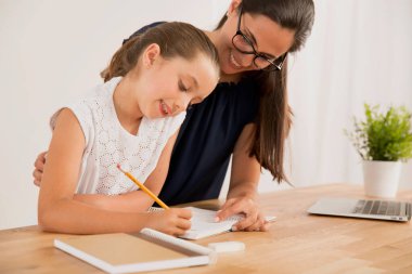 Genç anne, kızına ev ödevinde yardım ediyor.