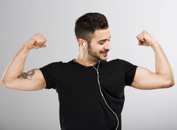 El hombre escucha música y mira sus músculos —  Fotos de Stock