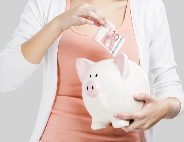 Kobieta oddanie pieniędzy w piggy bank — Zdjęcie stockowe
