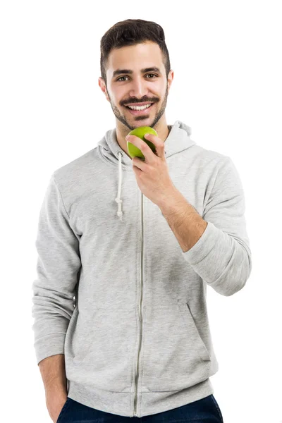 Mies maistaa vihreää tuoretta omenaa — kuvapankkivalokuva