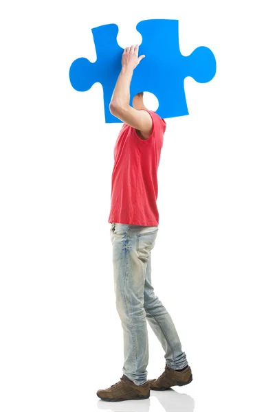 Young man holding a puzzle piece — Stock Photo, Image