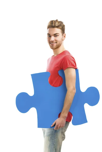Молодой человек держит кусочек головоломки — стоковое фото