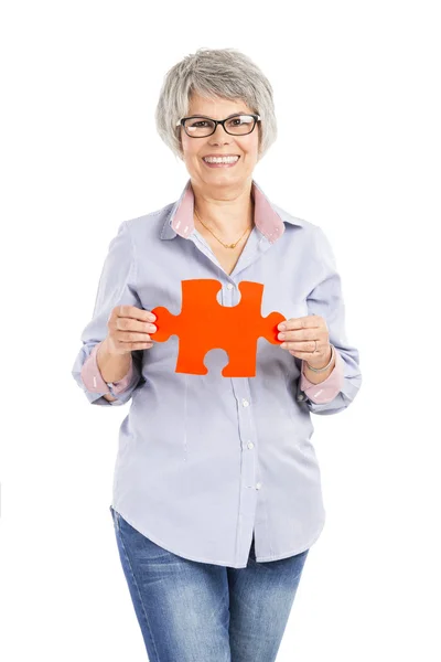 Elderly woman holding a puzzle piece — Stock Photo, Image