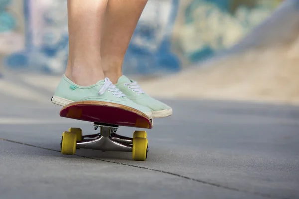 Donna piedi cavalcando uno skateboard — Foto Stock