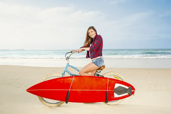 Surfer kvinna ridning cykel på stranden — Stockfoto