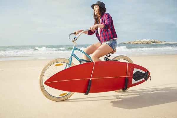 Surfer ung kvinna ridning cykel — Stockfoto