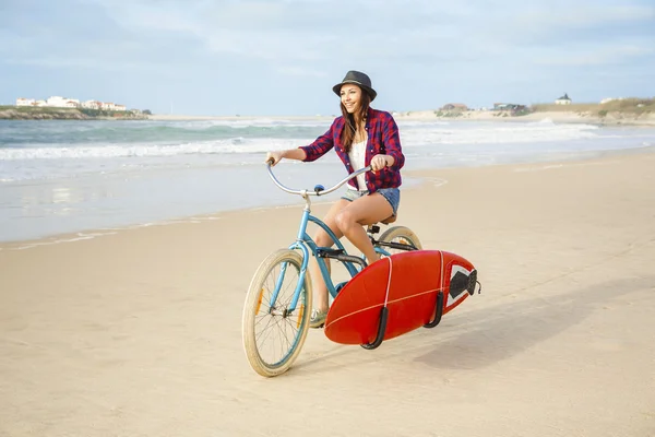 Surfer ung kvinna ridning cykel — Stockfoto