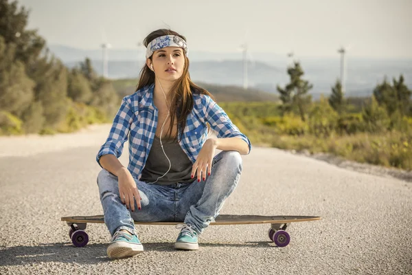 Жінка сидить над скейтбордом — стокове фото