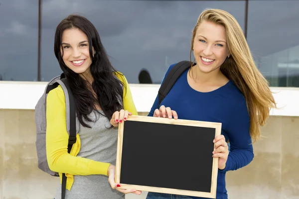 Adolescentes estudantes segurando quadro e sorrindo — Fotografia de Stock