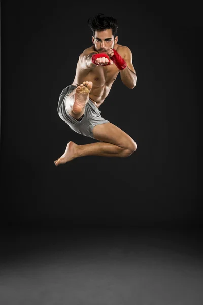 Atleta em bandagens de boxe pulando e chutando — Fotografia de Stock