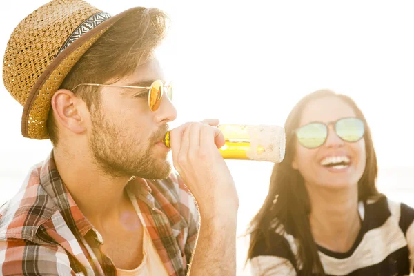 Jovem casal na praia bebendo cerveja — Fotografia de Stock