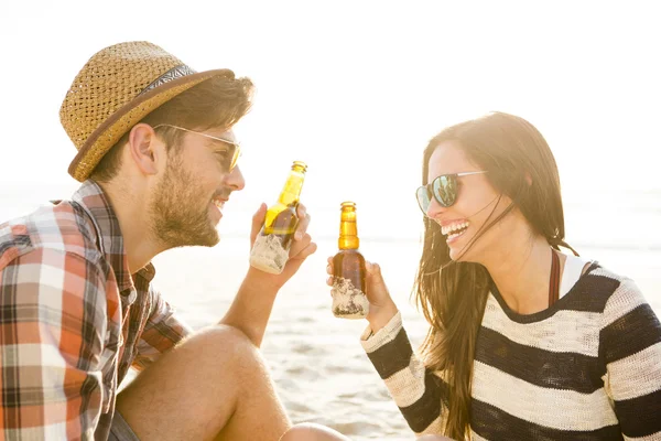 Jong koppel op het strand bier drinken — Stockfoto