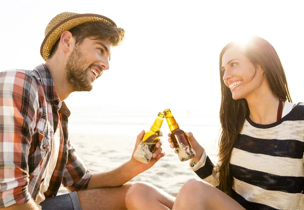 Молодая пара на пляже пьет пиво — стоковое фото