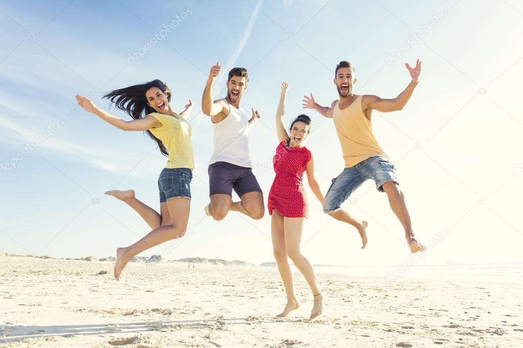 friends making a jump together at the beach
