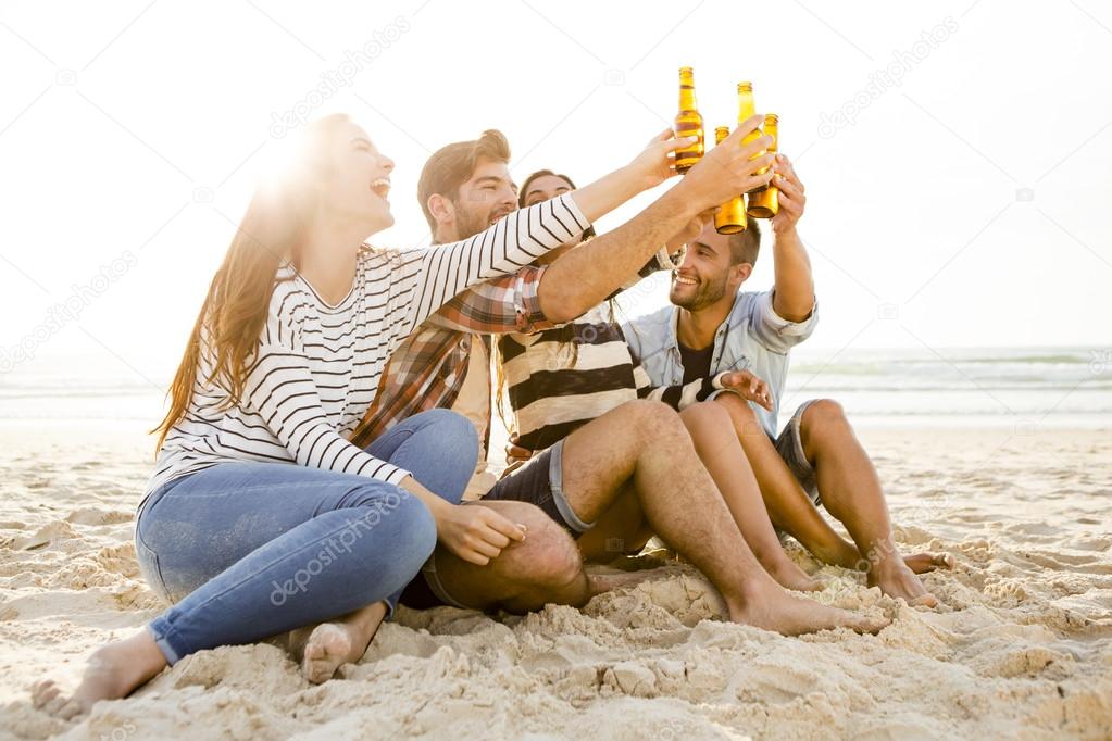 Friends drinking a cold beer at the beach