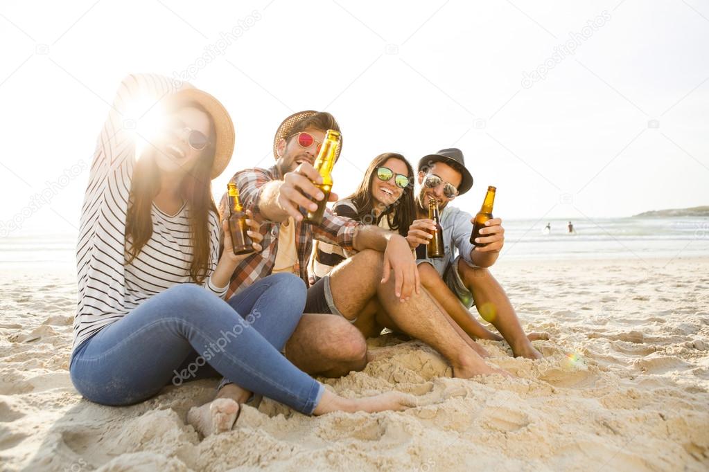 Friends drinking a cold beer at the beach