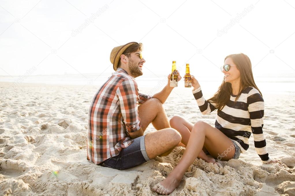 Young couple at the beach drinking beer