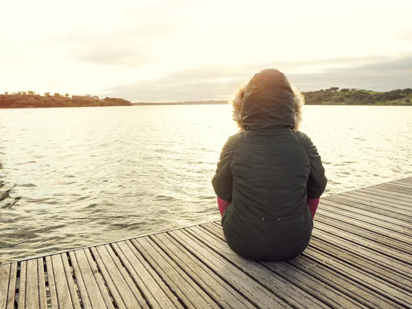 Frau sitzt an einem See — Stockfoto