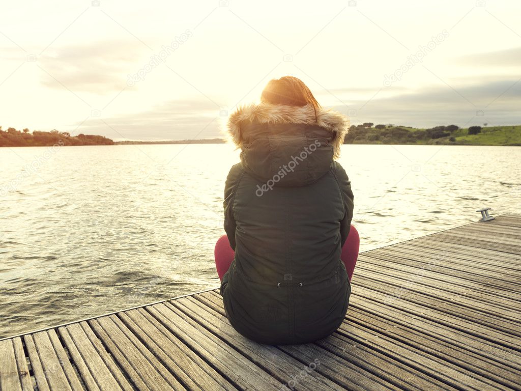 Woman sitting close to a lake