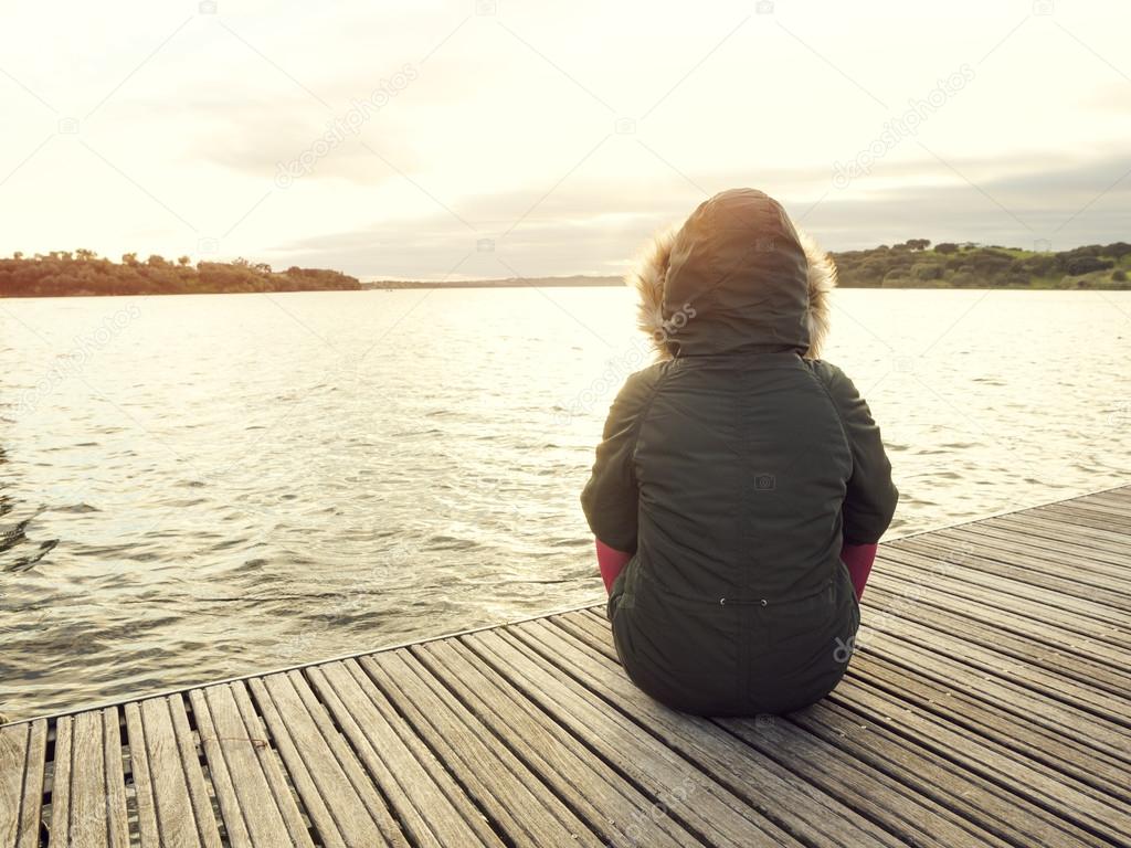 Woman sitting close to a lake