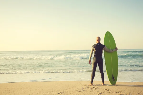 Surfer met surfplank en kijken naar de golven — Stockfoto