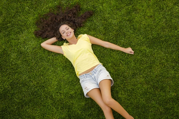Vacker ung kvinna liggande på gräset — Stockfoto