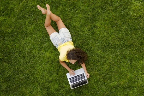 Vrouw die met een laptop werkt op gras — Stockfoto