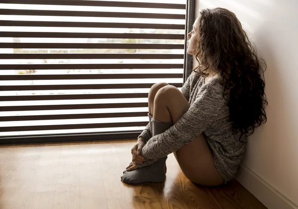 Jeune fille réfléchie regardant vers la fenêtre — Photo