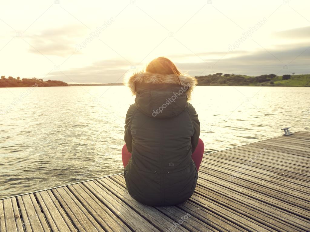 Woman sitting close to a lake